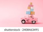 Small photo of Love composition made of teddy bear and Pink toy car delivery gift boxes on pink background. Minimal concept of Valentine's Day or love. Creative art,minimal aesthetics, writing space and copy space