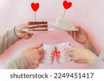 a man and a woman hold in their hands plates with a cake decorated with a red heart-shaped lollipop and mugs with hearts. Couple in love celebrating Valentine's Day