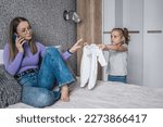 Small photo of a little girl asks her mother to give birth to her brother or sister, the mother is talking on the phone and brushing off the child. The unwillingness of a woman to give birth, one child in the family