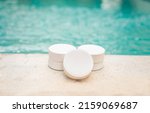 Small photo of Close-up of some chlorine tablets for cleaning on the edge of a swimming pool, chlorine tablets to clean swimming pools, concept of chlorine tablets to disinfect swimming pools