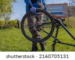 Man reparing bicycle wheel. Cyclist changing tire diy. Looking for bicycle tires leak. Examining bike for issues in park. Back bicycle tire wobbles problem solving.