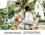 Young asian woman artist painting on canvas.Female artist drawing with inspiration in garden