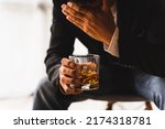 Alcoholism, depressed asian young man sleep on table while drinking alcoholic beverage, holding glass of whiskey alone at night. Treatment of alcohol addiction, suffer abuse problem alcoholism concept