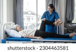 Small photo of Asian female physiotherapist helping senior older woman stretching hamstring, Rehabilitation physiotherapy, elderly. Causes knee pain, swelling, redness, stiffness in knee, clunking noise in knee.