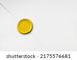 Bright yellow blank circular wax seal against white paper.