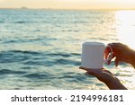 Small photo of mug mockup. sublimation white mug mockup holding by girl in seascape. white sublimation cup for cup seller and designer for e-commerce and online sales. increase sales because of the great background