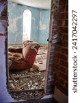 Small photo of Abandoned Red Armchair in Decayed Room with Arched Window Forgotten Interior View