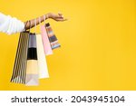 Sale offer. Black Friday. Shopping discount. Closeup of Afro woman hand holding purchase bags isolated on orange empty space background.