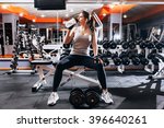 Professional  bodybuilding athlete relax after exhausting training.  Athlete relax and drink  water from sport bottle in gym interior.