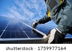 Small photo of Close up of man technician in work gloves installing stand-alone photovoltaic solar panel system under beautiful blue sky with clouds. Concept of alternative energy and power sustainable resources.