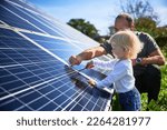 Small photo of Man showing his small child the solar panels during sunny day. Father presenting to son modern energy resource. Little steps to alternative energy.