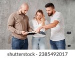 Small photo of Man and woman looking at catalogue while choosing interior design for new apartment with professional designer. Couple planning home renovation and redesigning with specialist.