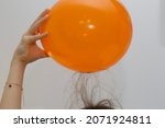 Small photo of A child raises their hair whilst exploring static electricity with an inflated orange balloon.