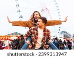 Happy couple having fun at amusement park in London - Portrait of young couple in love enjoying time at funfair with rollercoaster on background - Happy lifestyle and love concepts