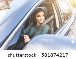Young woman driving a car in the city. Portrait of a beautiful woman in a car, looking out of the window and smiling. Travel and vacations concepts