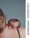 Small photo of Newborn in his mother's arms looks at camera with sympathetic expression