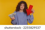 Small photo of Upset curly haired woman showing red arrow pointing down, concept of downgrade, unsuccessful business, fall of stock market money dollar exchange rate bankruptcy fail. Young girl on yellow background