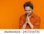 Small photo of Sneaky cunning Caucasian young man with tricky face gesticulating and scheming evil plan, thinking over devious villain idea, cheats, jokes pranks. Guy isolated on orange studio background. Copy-space