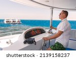 Small photo of Man stand at the helm of yacht and looking forward at the sea