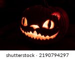 Small photo of Halloween jack-o-lantern pumpkin cheshire cat face with candle light scary cat