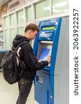 Small photo of Young man with a backpage buying tickets from a vending machine in a subway station