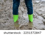 Rubber boots stuck in mud. Dirty rubber boots of green color on a dirt road. Dirty waterproof shoes, autumn concept.