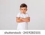 Small photo of Negative human emotions, reactions and feelings. Isolated shot of moody displeased angry little boy crossing arms on his chest, pouting lips, having offended facial expression, being capricious