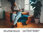 Small photo of Beautiful Young Hipster Girl in casual clothes Learning to play ukulele guitar sitting on wooden stairs at home, Young Beginner Woman playing ukulele, Hobby leisure Time Learning Concept