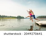 	
Group of teenage kids jumping off the dock into the lake together during a fun summer vacation.	
