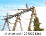 Power line station, high voltage transmission tower post tension for electricity distribution. Pylon construction with cables. Energy supply, conservation, urban industry concept. Blue sky, town city