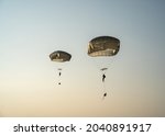 United States Army Soldiers and Paratroopers descending in the sky, from an Air Force C-130 military aircraft during an Airborne Operation.