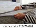 Small photo of Cropped shot of man showcasing the waterproof topper for white orthopedic mattress. Male showing hypoallergenic foam matress protector. Close up, copy space, top view, background.