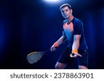 Squash player on a squash court with racket. Man athlete with racket on court with neon colors. Sport concept. Download a high quality photo for the design of a sports app or betting site.