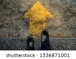Small photo of Start and Challenge Concept. a Business Man on Formal Shoes Steps to Follow a Yellow Arrow, Get Ready to Moving Forward or take a Chance to Success. Top View