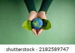 Small photo of World Earth Day Concept. Green Energy, ESG, Renewable and Sustainable Resources. Environmental and Ecology Care. Hands of Person Embracing Green Leaf and Craft Globe