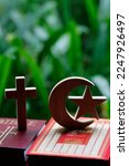 Small photo of Religious symbols : Muslim Crescent and Star with Quran, and Christan Cross with Bible. Interreligious or interfaith dialogue concept.