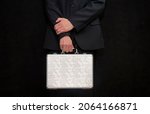 Small photo of A man in a suit with a suitcase handcuffed on a black background, close-up, selective focus, dark tonality. Concept: secure delivery of money and documents, business courier, classified information 1.