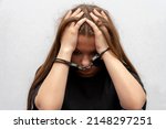 Small photo of A young girl handcuffed on a gray background, close-up. Juvenile delinquent in a black T-shirt, criminal liability of minors.