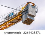 Small photo of Boom tower crane with engine and counterweight. A tower construction crane on the background of a blue sky with clouds. Boom rotary crane with boom. Construction of apartment buildings in the city.