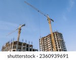 Small photo of Construction of multi-apartment high-rise buildings in the city. Equipment for the construction and lifting of bulky loads during the construction of buildings. The tower crane lifts the load.