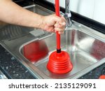 Small photo of A man clears a blockage in a kitchen sink pipe. Domestic work