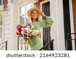 Small photo of beautiful young woman in summer style outfit smiling happy walking with flowers in city street wearing straw hat fashion trend, peony garden