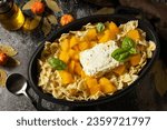 Fetapasta. Baked feta pasta, or Tiktok pasta. Feta pasta recipe made of pumpkins, feta cheese, garlic and herbs on dark stone background. 