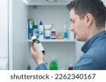 Man hold medication bottle reading instruction or prescription on packaging. Man looking at bottles from medicine cabinet
