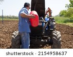 Small photo of Farmer putting diesel fuel to the tractor with a jerrycan. Reference to expensive fuel in the agricultural sector