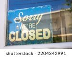 Small photo of Sign in the shop window behind a pane of glass saying 'Sorry we're closed'. the shop is closed. end of business. closure of business. modern font.