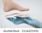 Small photo of Orthopedic insole isolated on a white background. Hands in rubber gloves hold an orthopedic insole. Foot care, comfort for the feet. Doctor orthopedist tests the medical device. Flat feet correction.