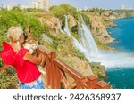 Small photo of woman cradles her cat at Duden Waterfalls in Antalya, Turkey. Dramatic backdrop of both Upper and Lower Duden, with latter cascading directly into the sea, transforms the scene into natural spectacle.
