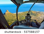 Helicopter cockpit flies in Lion's Head, coast and Cape Town in South Africa, with pilot arm and control board inside the cabin.