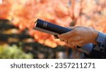 Small photo of Red maple leaves, autumn, and a Christian who spreads the gospel and evangelizes by passing the holy Bible with both hands